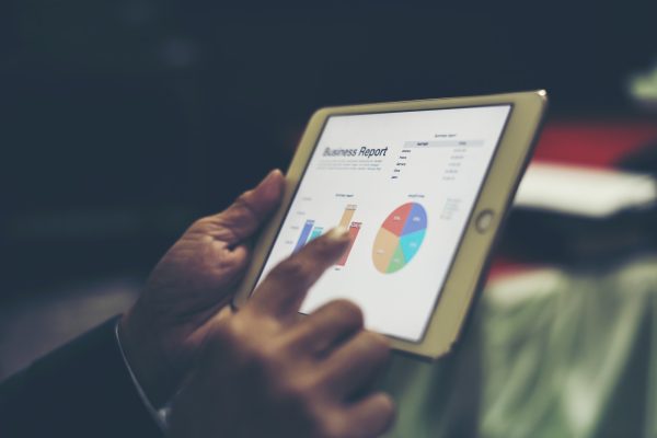 Business person hand holding financial statistics displayed on the tablet screen at office.